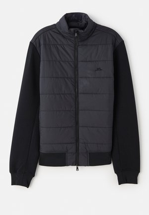 Puffer jacket with a black padded front and solid black knit sleeves. Features a zip closure and high collar design.