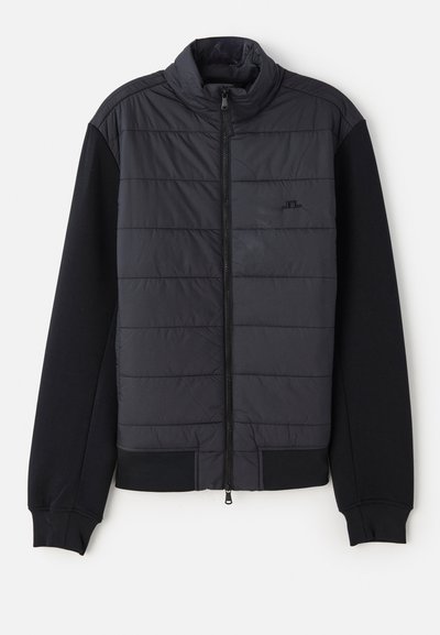 Puffer jacket with a black padded front and solid black knit sleeves. Features a zip closure and high collar design.