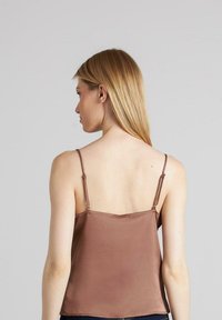 Camiseta de satén marrón con tirantes delgados ajustables, que presenta una textura suave y una silueta sencilla, diseñada para un ajuste ceñido.