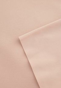 Twee overlappende stukken gladde, zachte stof in een lichte perzikkleur, met een matte afwerking en subtiele textuurvariaties.