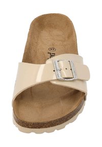 Beige slide sandaal met een gepatineerd oppervlak, een textuur van kurken voetbed en een metalen gesp accent. Rond toelopend en open rug ontwerp.