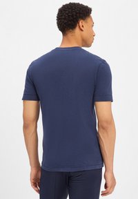 Granatowa koszulka z krótkim rękawem z okrągłym dekoltem, wykonana z miękkiej bawełny. Charakteryzuje się minimalnymi detalami szycia i luźnym krojem.