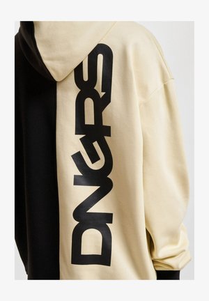 Mikrofibra ar pārslēgtu dizainu krēmkrāsā un melnā krāsā, ar lieliem melniem burtiem "DNGRS" krēmkrāsas pusē. Mīksta tekstūra.