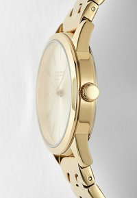 Guldtonad armbandsur med rund klockkropp, slät bezel och en ljus urtavla. Utrustad med ett texturerat, länkad band och en sidokrona.