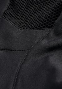 Zwarte stof met een gladde textuur heeft een gaas paneel, wat contrast en ademend vermogen creëert, met naadloze stiksels zichtbaar.