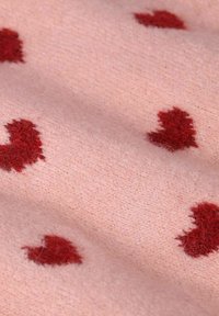 Tissu rose doux avec de petits motifs de cœurs rouges flous dispersés uniformément sur la surface.