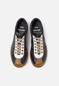 Black leather sneakers with white and brown accents, featuring a rounded toe, lace-up front, and textured rubber sole.