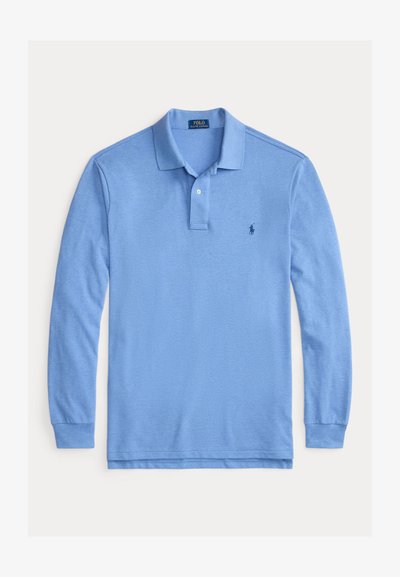 Svetlo modra dolga polo majica iz bombaža. Ima zapenjanje na dva gumbka, rebrovane manšete in majhen logotip na levem prsnem delu.