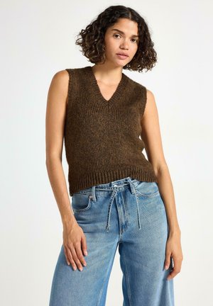 Maglione senza maniche di colore marrone a maglia con scollatura a V, caratterizzato da una finitura texture. Abbinato a jeans in denim chiaro a vita alta.