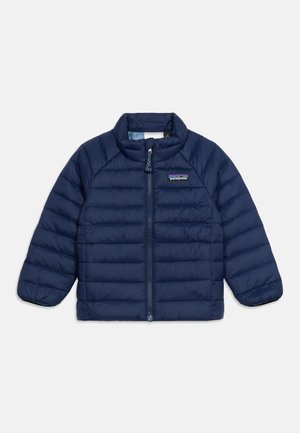 Mörkblå vadderad jacka med hel dragkedja framtill, hög krage och elastiska muddar, med en liten Patagonia-logotyp på bröstet.