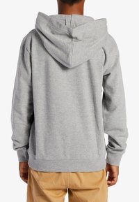 Grå sweatshirt med huva, med långa ärmar och ribbade muddar, visad bakifrån. Materialet verkar mjukt och avslappnat.