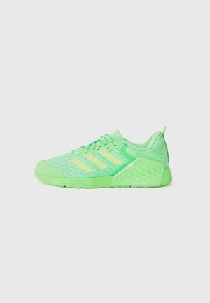 Lysegrøn atletiksneaker med mesh-overdel, tre blege gule striber på siden og tekstureret hælstøtte, vist på hvid baggrund.