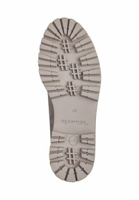 Suola di scarpa chiara con profonde scanalature, caratterizzata da un motivo testurizzato e un logo circolare. Marcata 'Toms' e con taglia '37' sulla superficie.