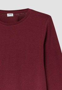 Bordeauxfarbene Langarmbluse mit rundem Halsausschnitt, aus weichem Baumwollmaterial mit glatter Textur und minimalen Nähdetails.