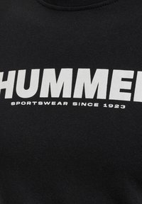 Svart sweatshirt med framträdande vit text som läser "HUMMER" och "SPORTSWEAR SINCE 1923" i en fet, blockig stil. Mjuk tygtextur.