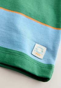 Kokvilnas T-krekls ar zaļām, zili oranžām horizontālām svītrām; ar uzšūtu etiķeti ar smaidošu seju; mīksts tekstūru.