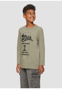 Olijfgroene T-shirt met lange mouwen en zwarte grafische tekst; casual pasvorm en zachte textuur; gecombineerd met grijze cargobroek met zijzakken.