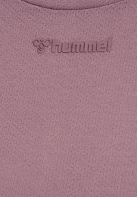 Helllila strukturiertes Gewebe mit einem subtilen Muster, das ein erhabenes "hummel"-Logo am Ausschnitt zeigt. Glattes, feuchtigkeitsableitendes Material.