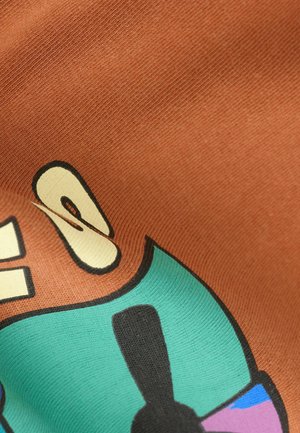 Cotton fabric in warm brown with a smooth texture. Features bold printed graphics in teal, yellow, and black with abstract shapes.