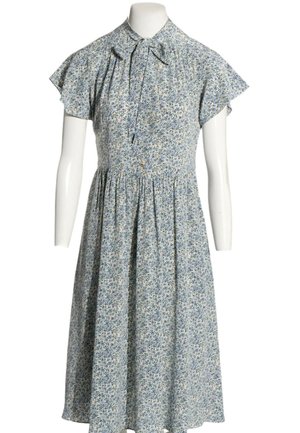Robe fleurie bleu clair avec manches courtes volantées, col haut et lien noué devant sur un buste de mannequin blanc.