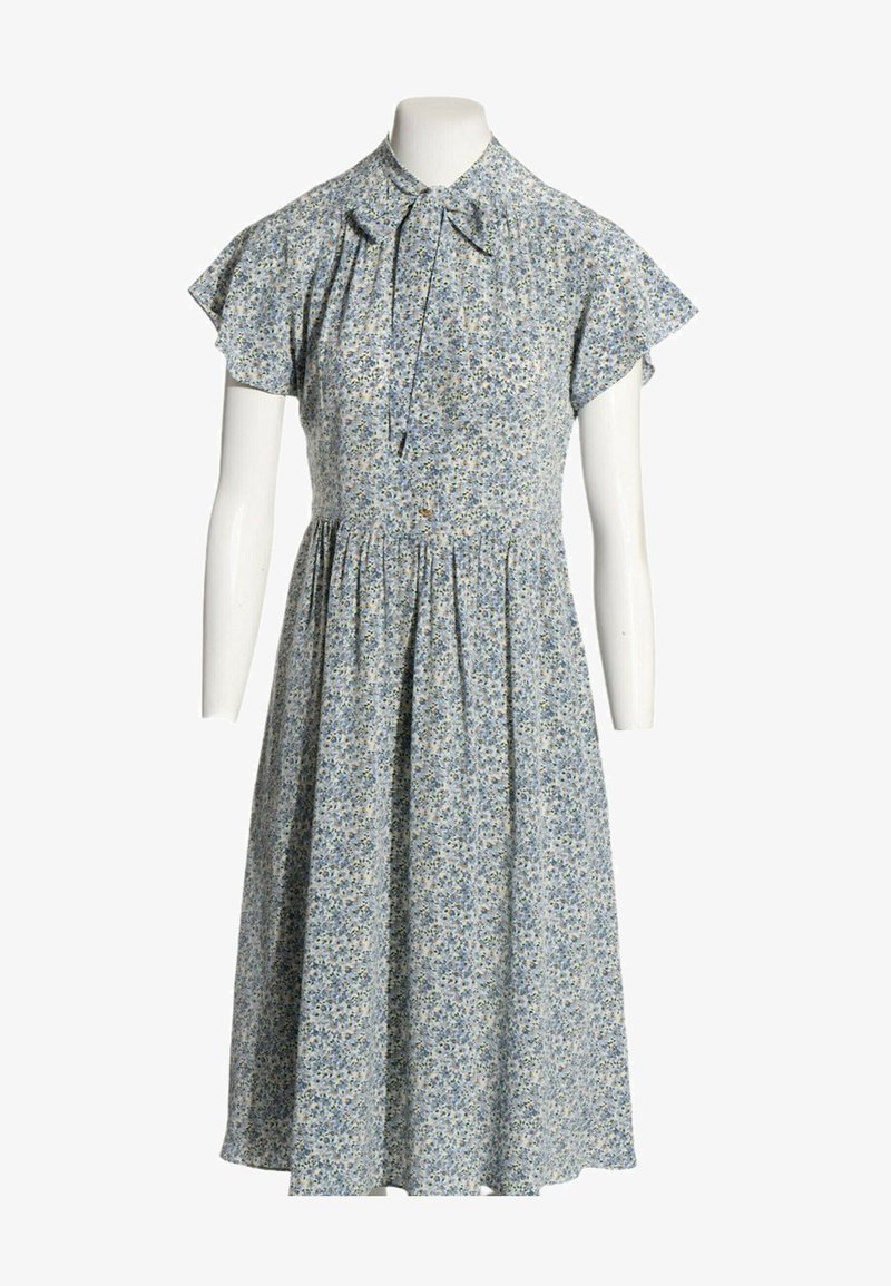 Robe fleurie bleu clair avec manches courtes volantées, col haut et lien noué devant sur un buste de mannequin blanc.