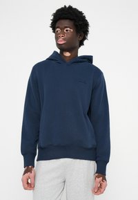 Felpa blu navy in tessuto morbido con tasca anteriore e cappuccio con cordino, caratterizzata da un logo sul petto e polsini a coste.