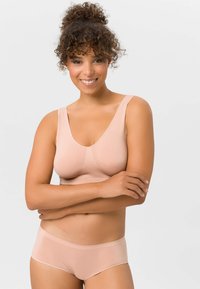 Leichter, nahtloser BH mit breiten Trägern in Nude-Farbe, kombiniert mit passendem Slip. Glatte Textur, einfaches Design, keine sichtbaren Beschläge.