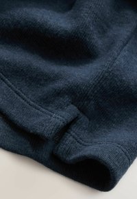 Dunkelblauer, gestrickter Stoff mit einer weichen Textur, sichtbar genäht und mit einem umgeschlagenen Saum. Keine ausgeprägten Muster oder Akzente.
