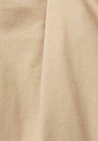 Tissu beige avec une fine texture en tissage diagonal, présentant des variations subtiles de teinte et une surface lisse. Idéal pour les vêtements ou le rembourrage.