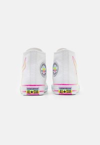 Weiße Canvas-Hochtop-Sneaker mit mehrfarbigen Akzenten, die runde Logos an den Seiten und eine bunte Sohle mit Markenlogo aufweisen.