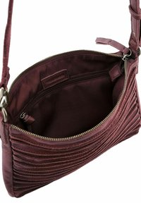 Sacs en cuir violet avec un extérieur plissé, fermeture éclair ouverte révélant un intérieur doublé en tissu et une poche zippée intérieure, sangle de shoulder attachée.