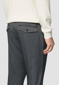 Grijze textuur broek met een slim fit, voorzien van twee achterzakken met knoopsluitingen en een subtiel herringbone patroon.