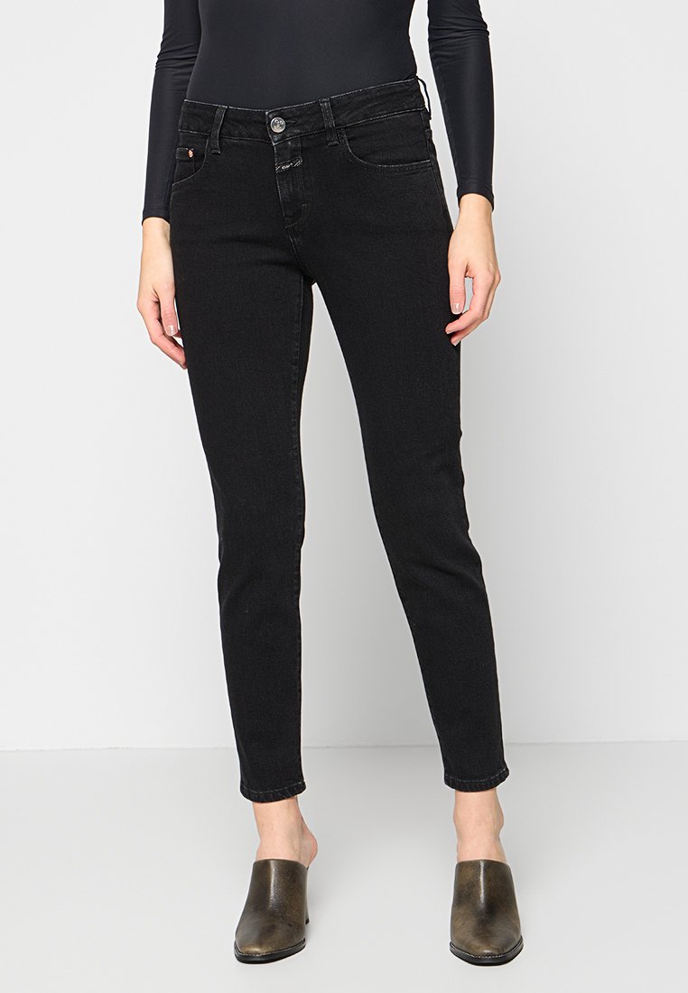 Schwarze schmale Jeans aus Denim, mit mittelhohem Bund, fünf Taschen und einem Knopfverschluss. Der Stoff hat eine glatte Textur und einen leichten Stretch.