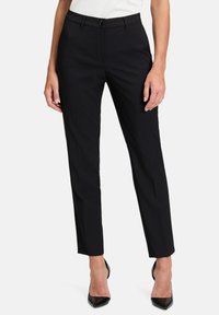 Čierne nohavice s priliehavým strihom, plochým predným dielom a jedným gombíkom na zapínanie. Hladká tkanina s jemným leskom, bez viditeľných vzorov.