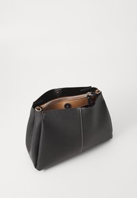 Borsa nera strutturata con forma rotonda, dotata di chiusura con zip, accenti di cucitura contrastanti e un interno marrone.