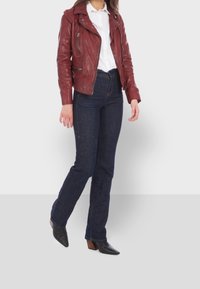 Burgundy lädermotorcykeljacka med silverdragkedjor, bärs över en vit skjorta. Kombineras med mörka denimjeans och svarta spetsiga klackskor.