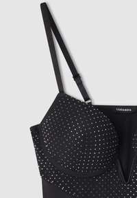 Top nero senza maniche con sottili spalline regolabili, coppe imbottite decorate con piccoli borchie argentate e dettagli con scollatura a V.