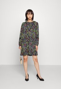 Vestido florido com mangas longas, base preta com flores verdes, vermelhas e roxas. Inclui um delicado acabamento em renda e um corte solto.