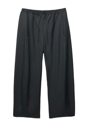 Schwarze weite Hose mit elastischem Bund und Kordelzug, ausgestattet mit seitlichen Taschen, vor einem weißen Hintergrund.
