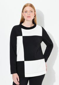 Maglietta a maniche lunghe con un motivo geometrico a blocchi in bianco e nero, realizzata in tessuto liscio con collo a scialle e orlo dritto.