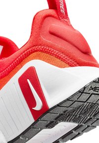 Rode en witte sneaker met een gestructureerde stofbovenkant, voorzien van een opvallend swoosh-logo, een gevoerde hak en een zwarte rubberen buitenzool met groeven.