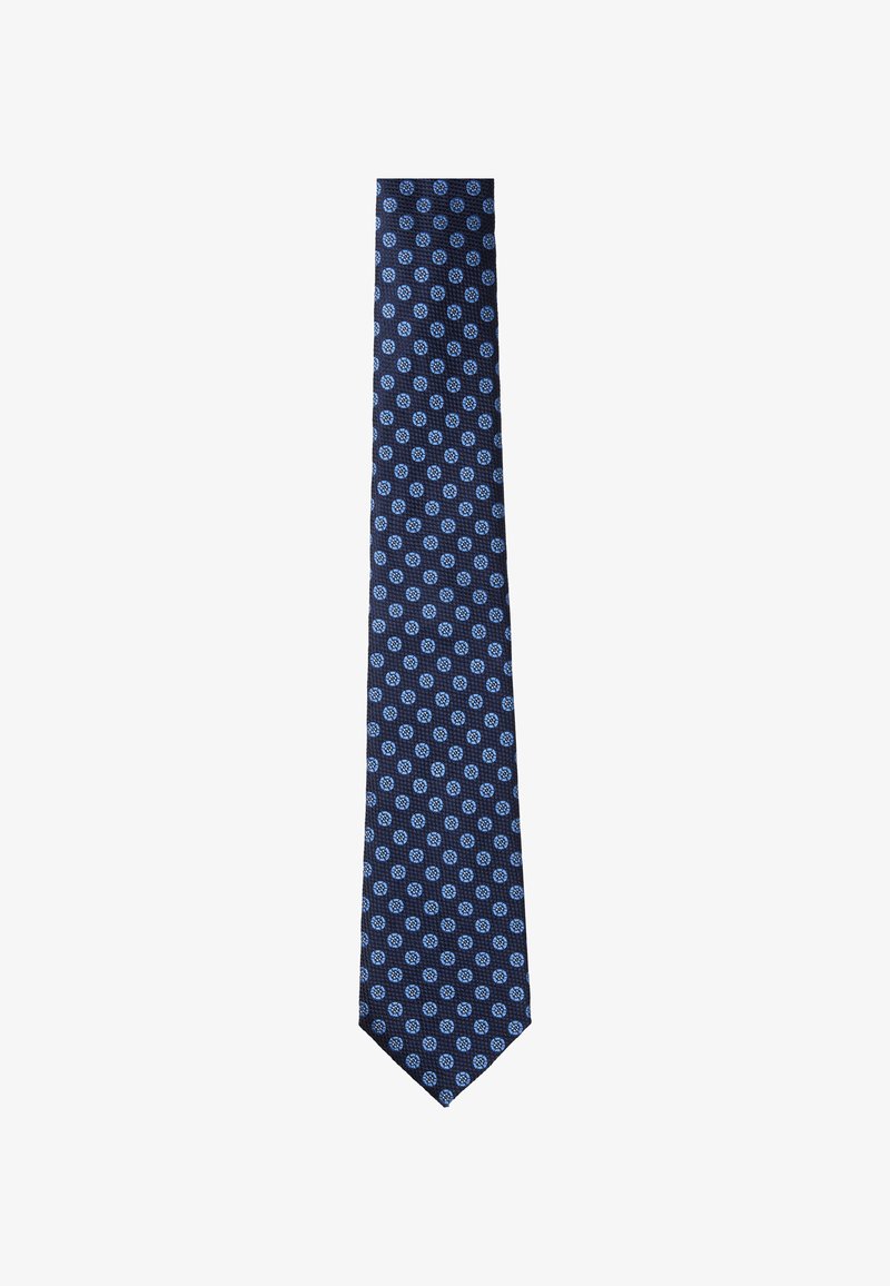 Cravate bleu marine ornée d'un motif répétitif de petits cercles bleu clair. Fabriquée dans un tissu texturé, elle présente un design classique effilé.