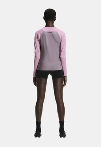 Top sport cu mâneci lungi, în nuanțe de roz deschis și gri, cu suprafață texturată, croială strâmtă și detaliu cu logo pe partea stângă jos.
