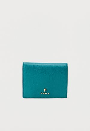 Πορτοφόλι από δέρμα σε τιρκουάζ με υφή, με το χρυσό λογότυπο Furla στο κέντρο της μπροστινής πλευράς, τοποθετημένο σε απλό λευκό φόντο.