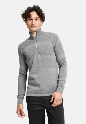 Grå pullovertrøje med halvlukket hals, tekstureret strikkemønster og ribbede manchetter. Bæret sammen med mørke slim-fit bukser.