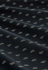 Tissu noir avec une texture lisse présentant un motif géométrique répété de petits triangles contourés en bleu clair et orange.
