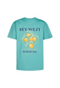 T-paita turkoosista puuvillasta, jossa on graafinen printti appelsiineista ja teksti "KEY-WEST PETROL IND". Lyhyet hihat ja tavallinen istuvuus.
