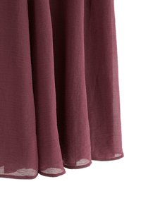 Bordeauxrød, letvægtsstof med en tekstureret overflade, der falder blødt med et blødt, flydende udseende, med kantede kanter og transparent kvalitet.