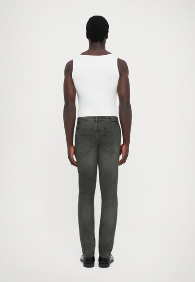 Fitted dark gray jeans with a smooth texture and subtle back pocket detailing, paired with a plain white sleeveless top.