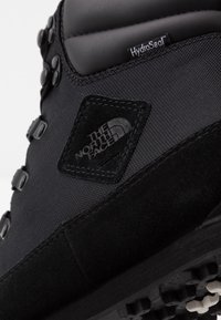 Gros plan d'une chaussure de randonnée noire North Face avec étiquette imperméable HydroSeal et semelle robuste.
